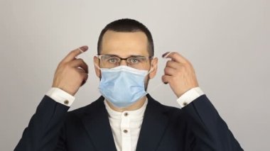 Genç ve başarılı bir iş adamı ortaklarıyla konuşurken tıbbi bir maske takar..