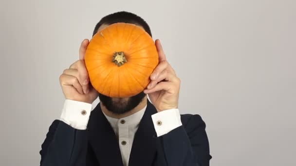 A young successful businessman holds a ripe organic pumpkin in his hands. Young handsome businessman is holding a pumpkin in his hands and getting ready for the halloween celebration. — Stock Video