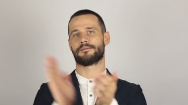 Yakışıklı genç adam alaycı bir şekilde gülümseyip ellerini çırpıyor..