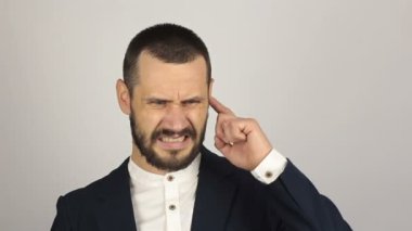 Genç ve başarılı bir iş adamının portresi. Kulağını karıştırıp suratını ekşitiyor. Genç ve başarılı bir işadamı kulağını eğlenceli bir şekilde karıştırıyor..