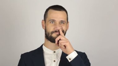 Genç ve başarılı bir iş adamı burnunu eğlenceli bir şekilde karıştırıyor. Genç ve başarılı bir iş adamının portresi. Burnunu karıştırıp suratını buruşturuyor..