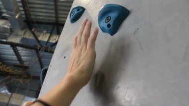 Spor salonunda yeteneklerini geliştiren bir kaya tırmanıcısının eli. Kapalı alanda kaya tırmanışı.