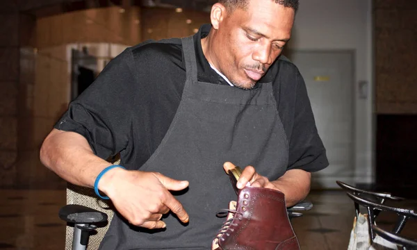 Master shoe shiner polishes brown boot in commerce building