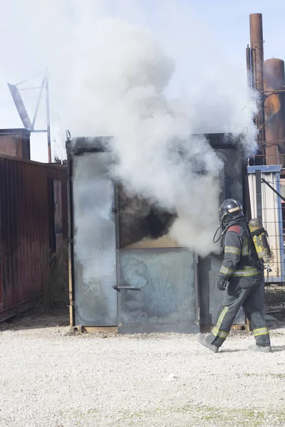 Firefighter putting out fire training station extinguisher backdraft emergency safety drill with ship container.