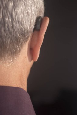 Modern dijital teknoloji işitme cihazı kulağına giyen sağır kıdemli vatandaş adam.