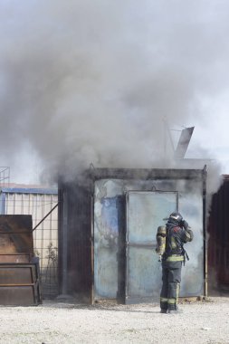 İtfaiyeci yangın söndürme istasyonunu söndürüyor. Acil durum güvenlik tatbikatı prosedürü..