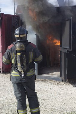 İtfaiyeci yangın söndürme istasyonunu söndürüyor. Acil durum güvenlik tatbikatı prosedürü..