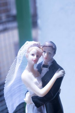 Düğün çifti pasta üstte plastik figürler smokin gece elbisesi, beyaz gelinlik peçesi.