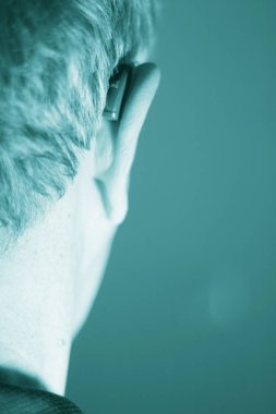 Modern dijital teknoloji işitme cihazı kulağına giyen sağır kıdemli vatandaş adam.