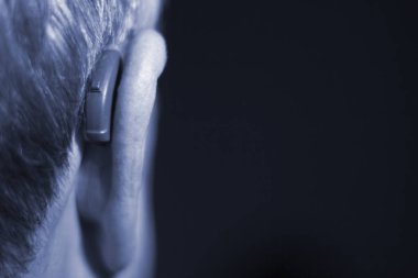 Modern dijital teknoloji işitme cihazı kulağına giyen sağır kıdemli vatandaş adam.