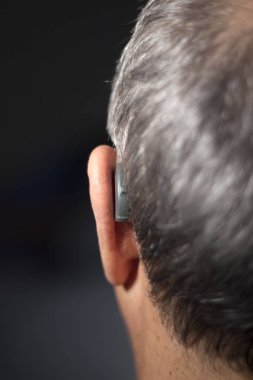 Modern dijital teknoloji işitme cihazı kulağına giyen sağır kıdemli vatandaş adam.