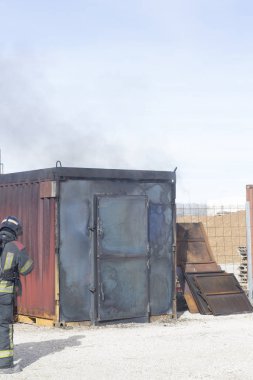 İtfaiyeci yangın söndürme istasyonunu söndürüyor. Acil durum güvenlik tatbikatı prosedürü..