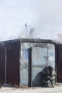 İtfaiyeci yangın söndürme istasyonunu söndürüyor. Acil durum güvenlik tatbikatı prosedürü..