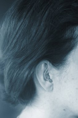 Sağır orta yaşlı Bayan modern dijital teknoloji işitme cihazı kulağına giyiyor.