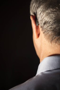 Modern dijital teknoloji işitme cihazı kulağına giyen sağır kıdemli vatandaş adam.
