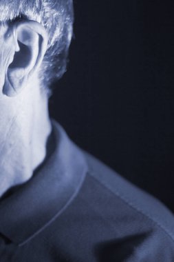 Modern dijital teknoloji işitme cihazı kulağına giyen sağır kıdemli vatandaş adam.