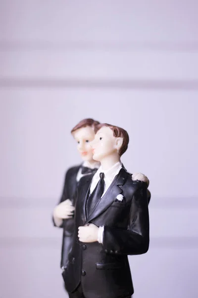 Cake topper gay wedding couple of two male grooms holding romantic marriage embrace of LGBT love.