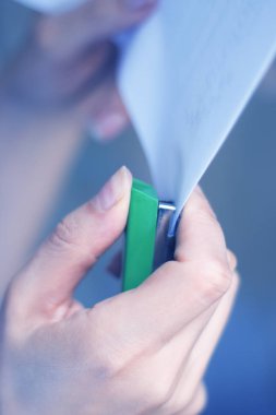 Genç bayanın elinde kağıt zımbalama office zımba tabancası.