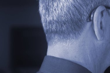 Modern dijital teknoloji işitme cihazı kulağına giyen sağır kıdemli vatandaş adam.