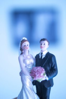 Düğün çifti pasta üstte plastik figürler smokin gece elbisesi, beyaz gelinlik peçesi.