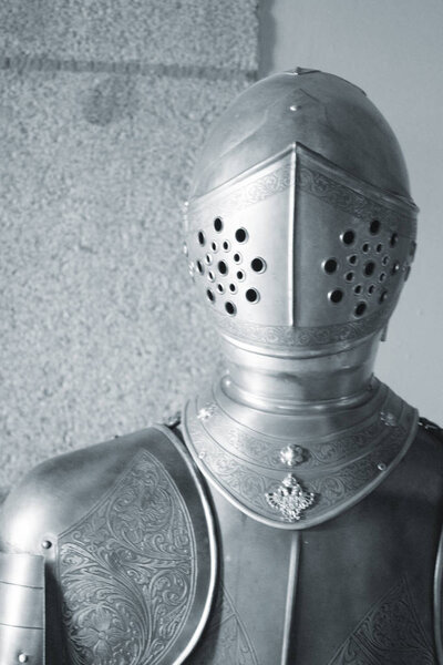 Medieval metal suit of armour and helmet worn by knight in middle ages castle.