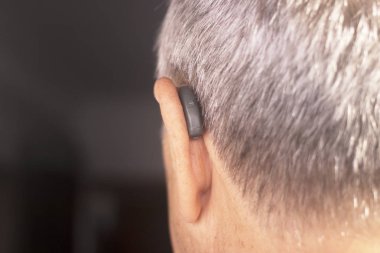 Modern dijital teknoloji işitme cihazı kulağına giyen sağır kıdemli vatandaş adam.