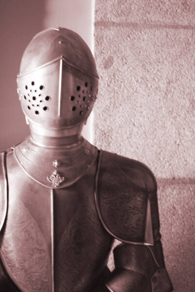 Medieval metal suit of armour and helmet worn by knight in middle ages castle.