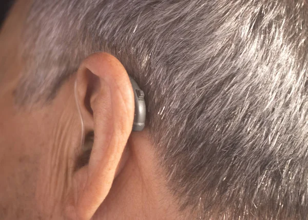 Modern dijital teknoloji işitme cihazı kulağına giyen sağır kıdemli vatandaş adam.