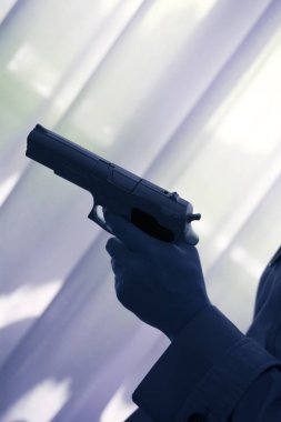 Otomatik tutan el silah siluet pencere ışık ile daki lüks otel yatak odasında tabanca.