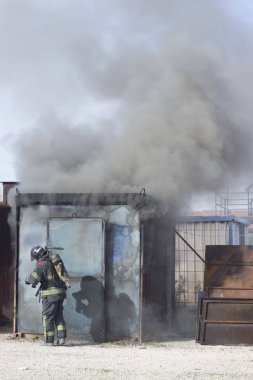 İtfaiyeci yangın söndürme istasyonunu söndürüyor. Acil durum güvenlik tatbikatı prosedürü..