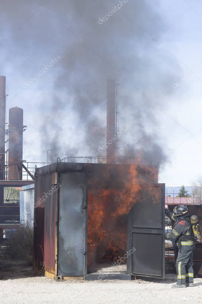 Firefighter putting out fire training station extinguisher backdraft emergency safety drill with ship container.