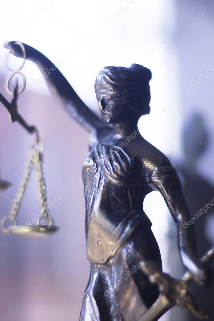 Legal law firm bronze statue of the goddess themis with scales of justice in attorneys office.