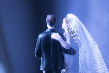 Düğün çifti pasta üstte plastik figürler smokin gece elbisesi, beyaz gelinlik peçesi.