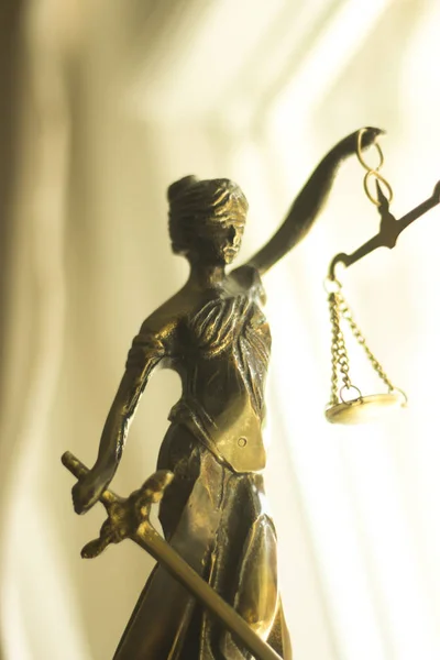 Legal law firm bronze statue of the goddess themis with scales of justice in attorneys office.