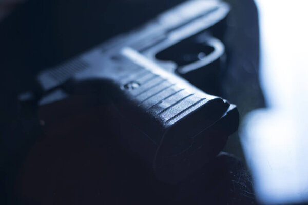 Automatic pistol handgun in artistic light effect moody atmospheric photo creative artistic closeup