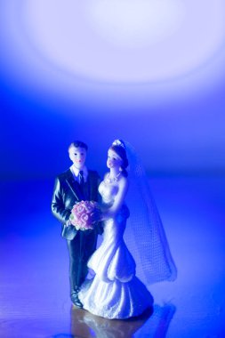 Düğün çifti pasta üstte plastik figürler smokin gece elbisesi, beyaz gelinlik peçesi.