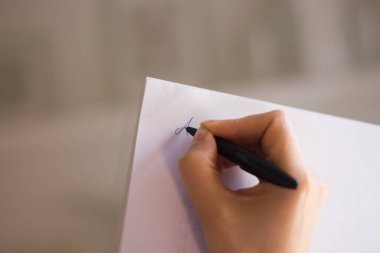Masada elinde kalemle kağıda yazan genç bayan..