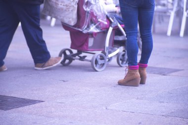 Kalabalık şehirde alışveriş caddesi kaldırımlarında yürüyen insanlar ayaklarında ve bacaklarında yük arabasıyla yürüyor..