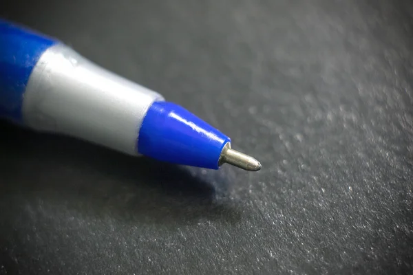 Tiro molhado de uma caneta esferográfica azul em um fundo preto — Fotografia de Stock