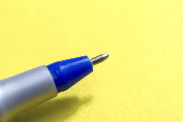 Wet shot of a blue ballpoint pen on a yellow background — Stock Photo, Image