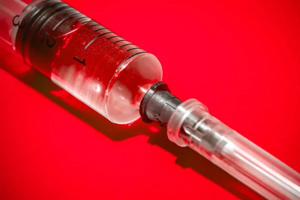 Empty syringe on red background, close up. Theme drug addiction — Stock Photo, Image