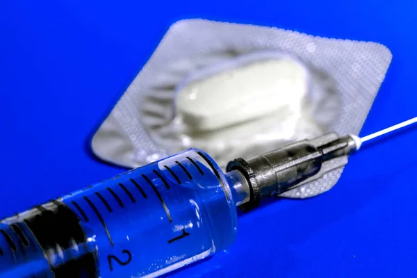 Ιατρική σύριγγα και χάπια σε μπλε φόντο, φάρμακο θέμα, θέμα τοξικομανία — Φωτογραφία Αρχείου