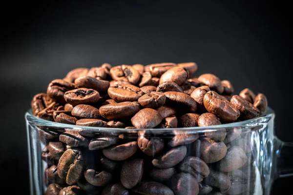 Mug transparan di dalam dengan biji kopi, semua dalam nada coklat, dalam kunci rendah, close up, tembakan makro — Stok Foto