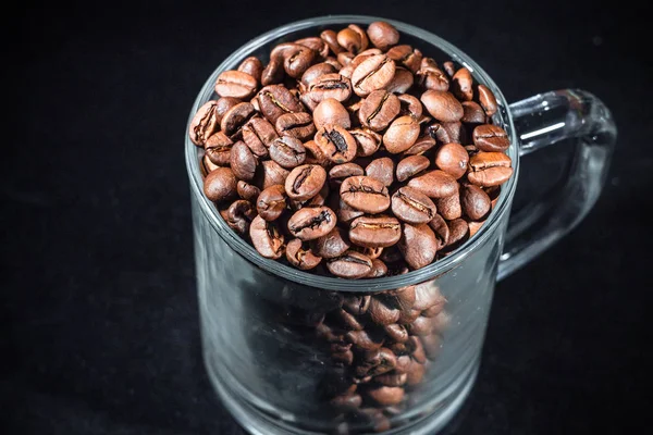 Gelas secangkir kopi dengan biji kopi pada latar belakang gelap, close-up, dalam kunci rendah — Stok Foto