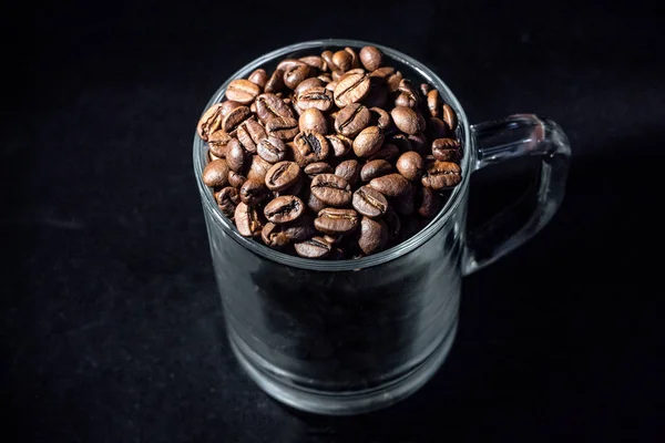 Gelas secangkir kopi dengan biji kopi pada latar belakang gelap, close-up, dalam kunci rendah — Stok Foto