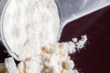 Plastik ölçüm kaşığı ve protein yığını, siyah tebeşir tahtası arka plan üzerinde peynir altı suyu