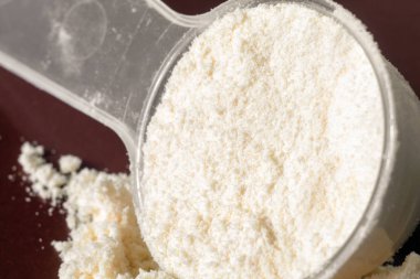 Plastik ölçüm kaşığı ve protein yığını, siyah tebeşir tahtası arka plan üzerinde peynir altı suyu