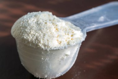 Plastik ölçüm kaşığı ve protein yığını, siyah tebeşir tahtası arka plan üzerinde peynir altı suyu