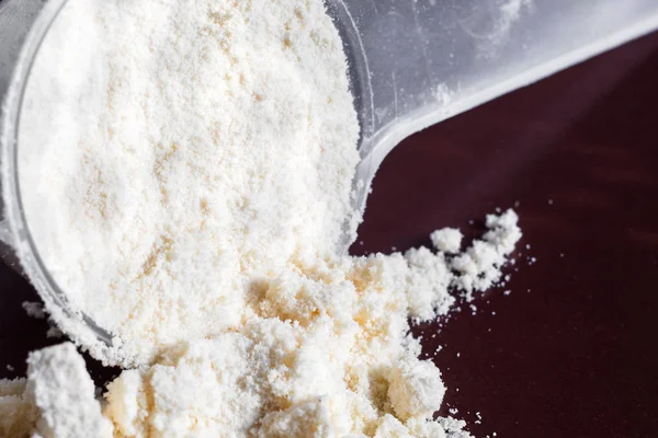 Plastik ölçüm kaşığı ve protein yığını, siyah tebeşir tahtası arka plan üzerinde peynir altı suyu