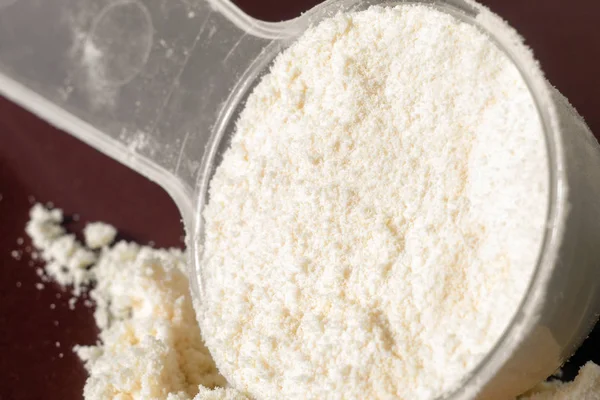 Plastik ölçüm kaşığı ve protein yığını, siyah tebeşir tahtası arka plan üzerinde peynir altı suyu